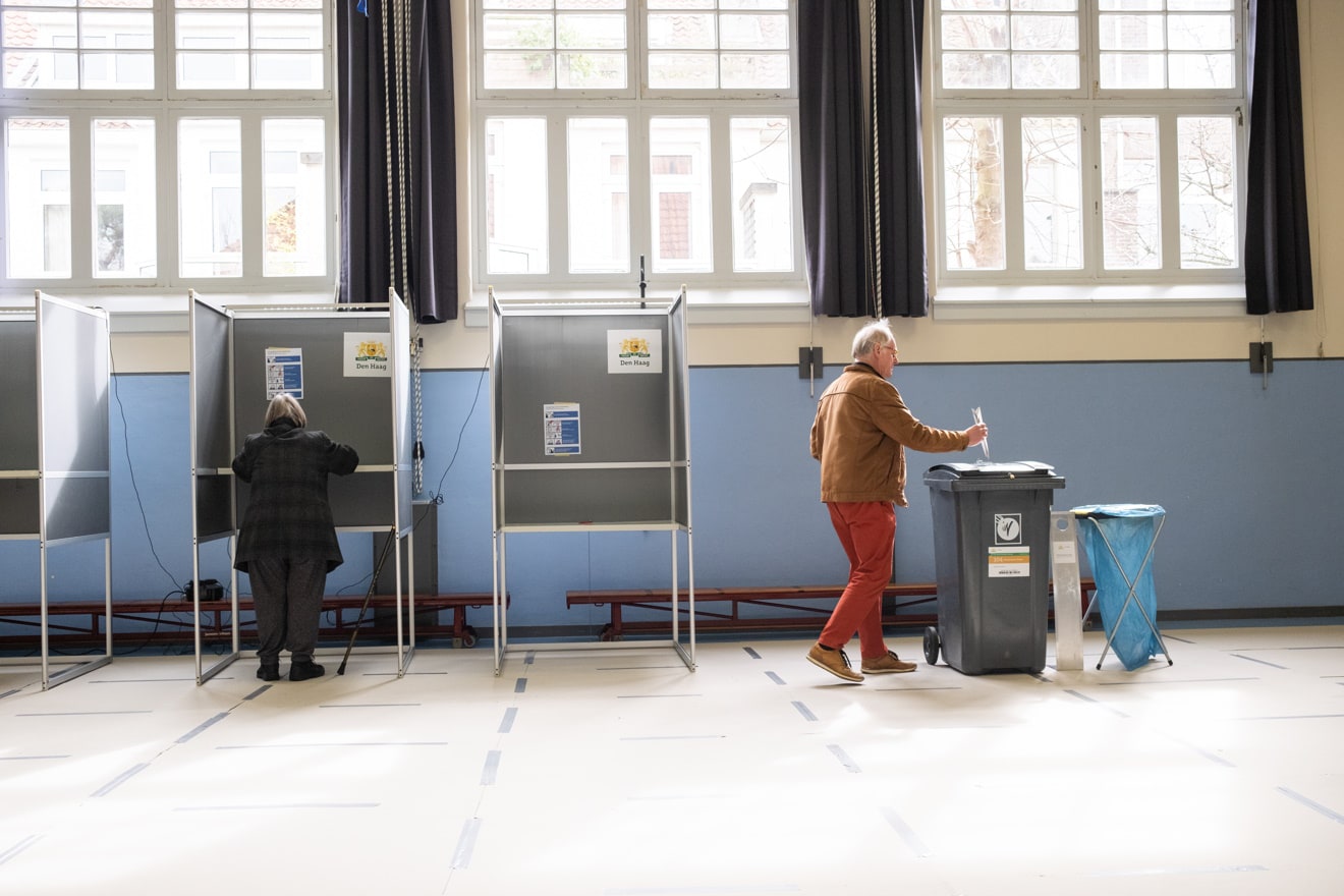 Overzichtsbeeld van een stembureau met stemmende mensen.