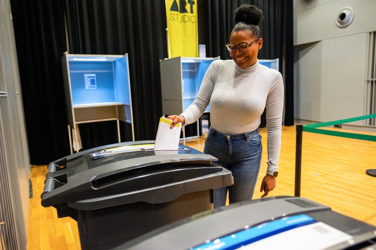 Jonge vrouw doet haar stembiljet in de stembus.